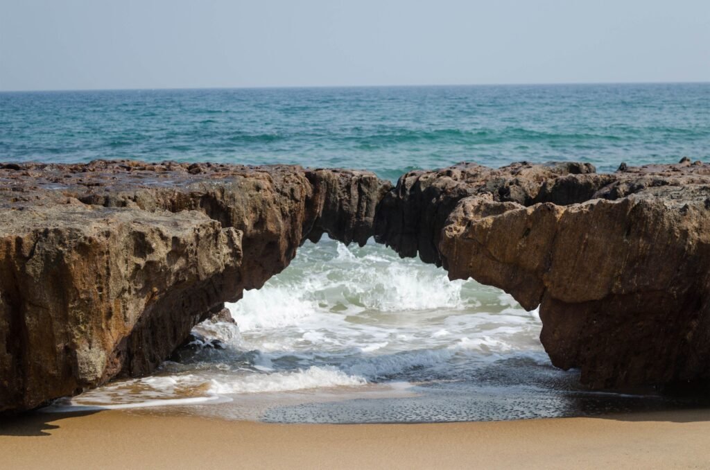 Beautiful rocky arch at Visakhapatnam beach with ocean waves crashing underneath.